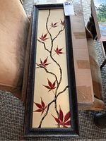 Full view of the framed artwork showing vertical canvas with a branching design and red leaves