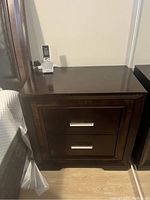 Photo of one Najarian nightstand showing two drawers with metal handles, dark wood finish, and scratches on surface.