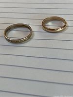 Both ladies wedding bands together showing size and material contrast.