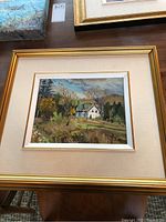 Framed oil painting of a rural scene showing a house and trees, signed AWB 96, with gold frame and beige mat