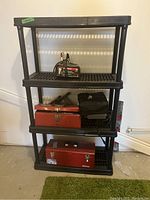 Side view of black plastic shelving unit holding battery charger, toolboxes, and soft case