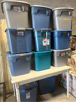 Stack of 11 assorted plastic storage totes in gray, blue, and teal with lids