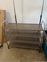 Full view of brown mesh shoe mat shelving unit with four tiers and metal frame