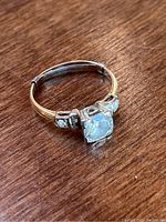 Ring front and side view showing center diamond and side stones on wooden surface