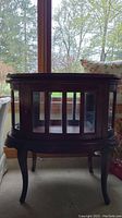 Front view of wood bar cabinet showing glass paned doors and ornate trim.