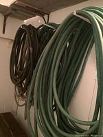Garden hoses coiled and hanging on basement wall.
