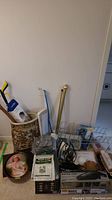 Lot includes multiple boxed and packaged home products plus umbrella stand with canes and a decorative trash bin.