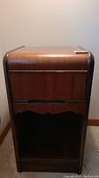 Front view of vintage wood night stand showing one handleless drawer and lower shelf with scalloped apron detail.