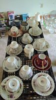 Overhead view of all teacups, saucers, and teapot arranged on a table, showing variety of colors and patterns