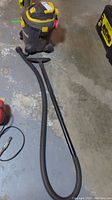 Full view of the Shop Vac with hose extended on a concrete floor.