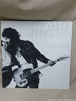 Front cover of Bruce Springsteen Born to Run vinyl album showing Springsteen holding guitar in black and white photo with title and artist name.
