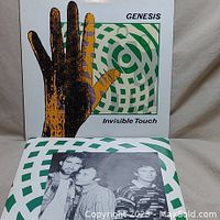 Front cover of Genesis Invisible Touch vinyl album showing hand with green and white geometric background and band name and album title