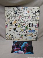 Front cover of Led Zeppelin III album with psychedelic butterfly and abstract art and Led Zeppelin logo. Postcard placed in front.