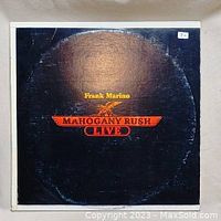 Front album cover of Mahogany Rush Live vinyl by Frank Marino with black background and red-yellow text.