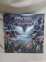 Front cover of the Saxon Rock the Nations vinyl album showing artwork of a crowd with flags and illuminated emblem.