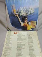 Front cover of the Supertramp Breakfast in America album, showing waitress holding orange juice with cityscape made of breakfast items in background, also view of inner sleeve with lyrics.