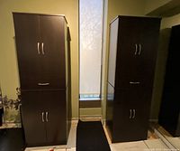 Two dark wood storage cabinets side by side in room near window, showing full front view.