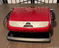 Closed George Foreman Evolve Grill System in red with digital controls on front, placed on table