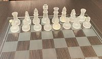Front view showing frosted glass chess pieces arranged on chess board with brown and clear checkered pattern.