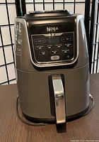 Full front view of Ninja Max air fryer showing control panel and handle with power cord at base.