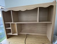 Front view of wood hutch showing multiple open compartments and scalloped top edge.