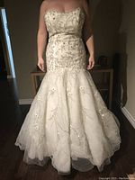 Front view of Lazaro strapless size 12 wedding dress featuring detailed beadwork and sparkles on fitted bodice and flared tulle skirt.