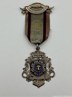 Front view of the antique sterling silver Masonic badge with ribbon showing details of the emblem and clasp.