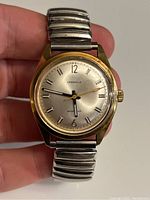 Front view of Caravelle vintage automatic watch with round gold-tone case and silver dial showing hands and hour markers.