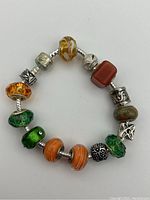 Full view of the charm bracelet showing various beads and charms on a serpent-style silver chain.