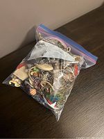 Freezer bag filled with assorted costume jewelry on a wooden surface