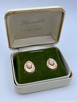 Open Krementz 14KT gold box with green velvet insert holding the pair of opal earrings