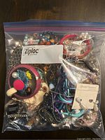 Full view of the costume jewelry inside a clear Ziploc freezer bag showing colorful bracelets, chains, and pearl-like beads.