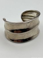 Angled view of silver cuff bracelet showing curved band design and smooth polished finish.