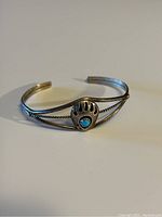 Front view of Navajo sterling silver bracelet with turquoise stone in bear claw centerpiece, showing twisted rope design detail