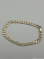 Silver curb link bracelet displayed in a loop with lobster claw clasp visible.