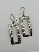 Front view of the pair of rectangular hammered sterling silver earrings with hooks, showing the textured surface.