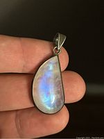 Close-up view of the labradorite pendant held in hand, showing the stone's color and silver setting.