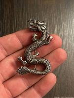 Front view of the dragon brooch held in hand showing the marcasite detailing and dragon shape