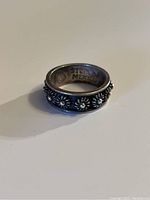 Side view of sterling silver ring showing raised floral pattern and oxidized finish.