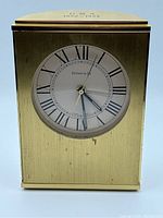 Front view of Tiffany & Co mantle clock showing Roman numerals and Tiffany & Co branding on clock face, with brass finish and visible minor wear.