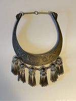 Photo showing the dark metal tribal necklace with detailed engraving and six tassel clusters