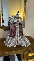 Front and angled view of W.M dress design mannequin dressed in Victorian style gown with dusty rose velvet fabric and intricate lace accents