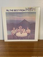 Front cover of 'All the Best from Prism' album showing band members around a table outdoors with mountain backdrop at sunset.