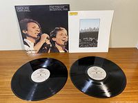 Two vinyl records and their album sleeves laid out on wooden surface