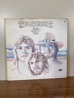Front cover of the Stampeders New Day album showing drawn portraits of the band members and album title.