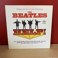 Front cover of The Beatles Help! vinyl record album, showing title and promotional text.