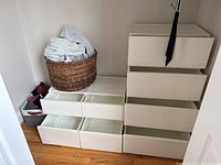 White plastic drawer units stacked in corner with laundry baskets on top and beside