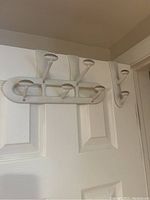 White plastic over-the-door hook rack mounted on door, five hooks.