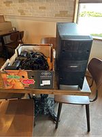 Photo of Bose Acoustimass bass module next to a box containing satellite speakers and wiring cables on a wooden table.