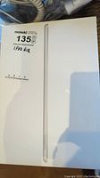 Side view of boxed iPad showing slim profile and label indicating 'IPAD AIR' on auction sticker.